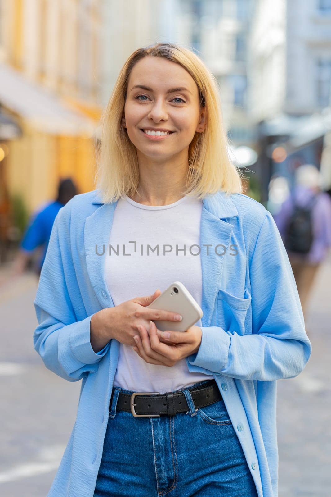 Tourist traveler young woman uses smartphone typing text messages looking for search a way on map in mobile navigator app outdoors. Caucasian lady female walking passes by urban city street background