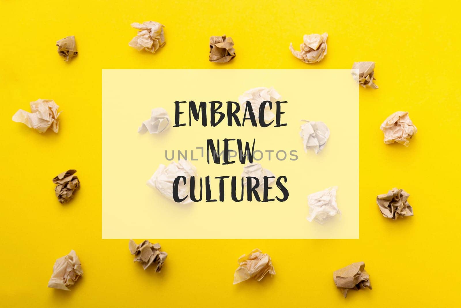 A yellow background with a bunch of crumpled paper on it. The paper is scattered in different directions and sizes. The text on the background reads Embrace New Cultures