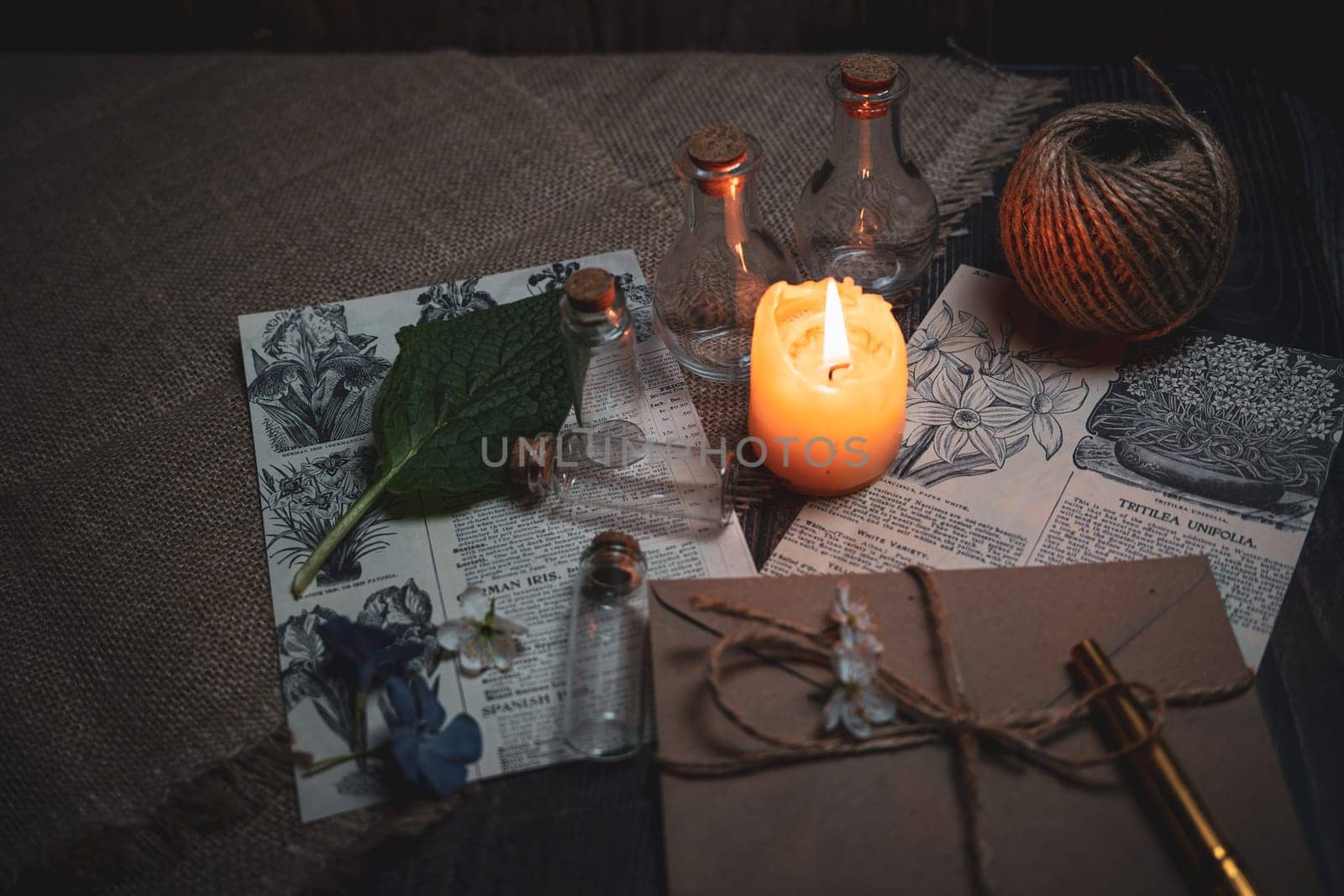 Mystical still life in vintage style with empty flasks, burning candles, letters and newspaper clippings. High quality photo