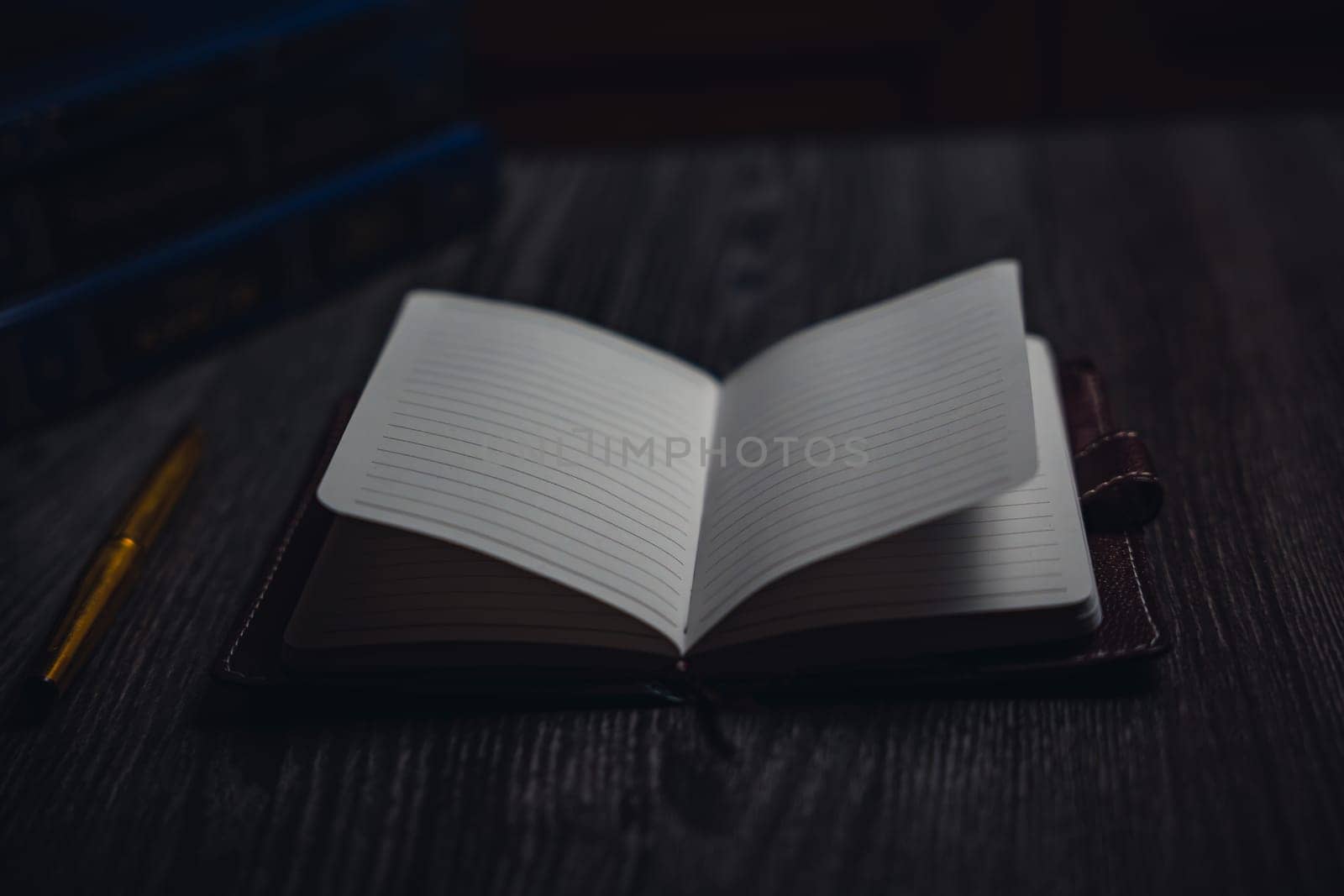 A notebook with a gold pen on the table in the candlelight. High quality photo