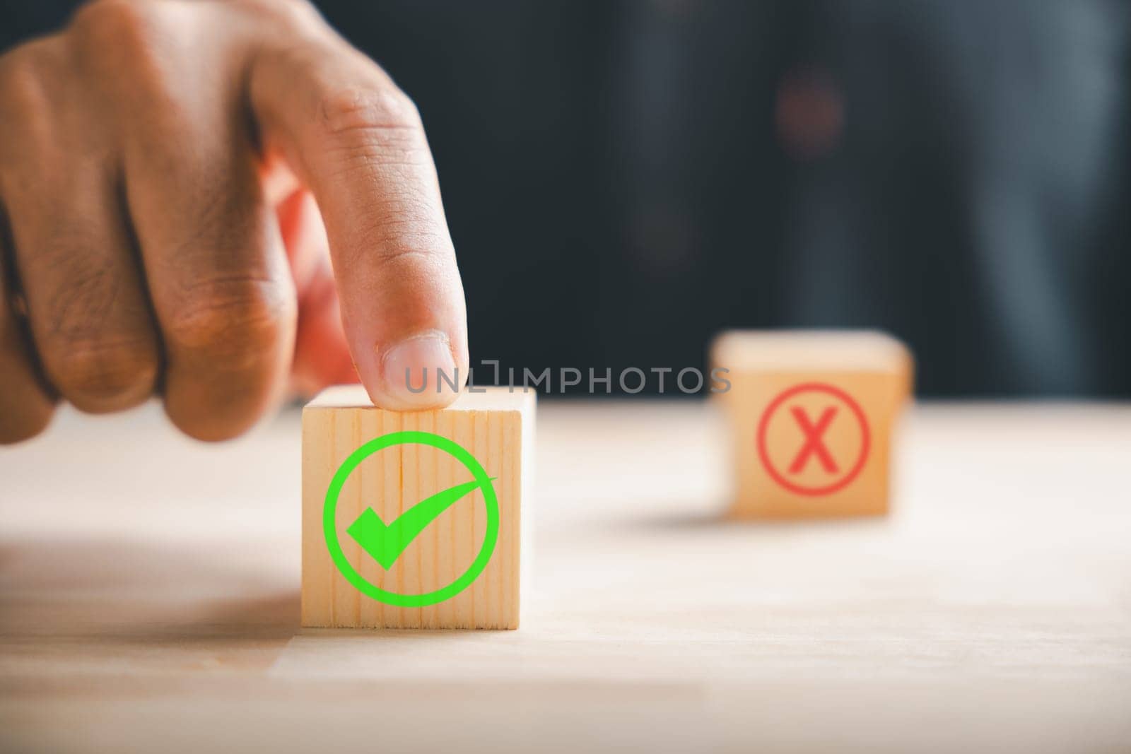 Businessman's finger points to two wooden cubes with check marks for right and wrong decisions. Choice and validation communication depicted. Think With Yes Or No Choice. by Sorapop