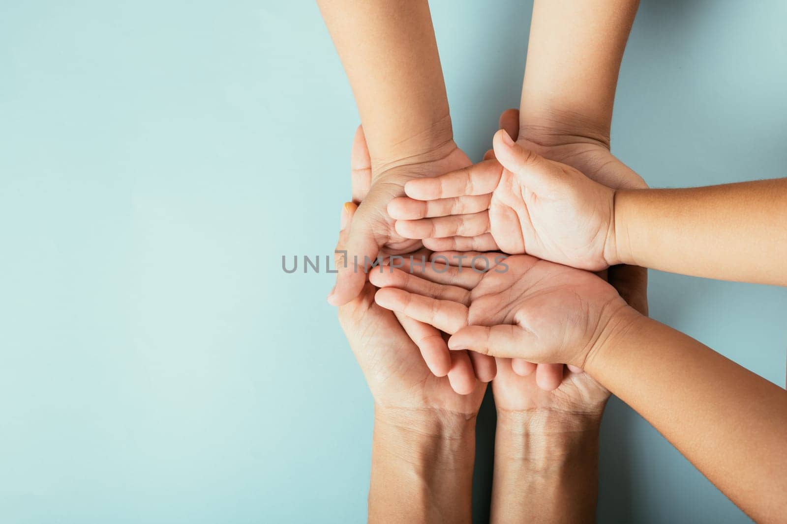 Family hands stacked in close-up top view isolated background. Parents and kid hold empty space symbolizing Family and Parents Day. by Sorapop