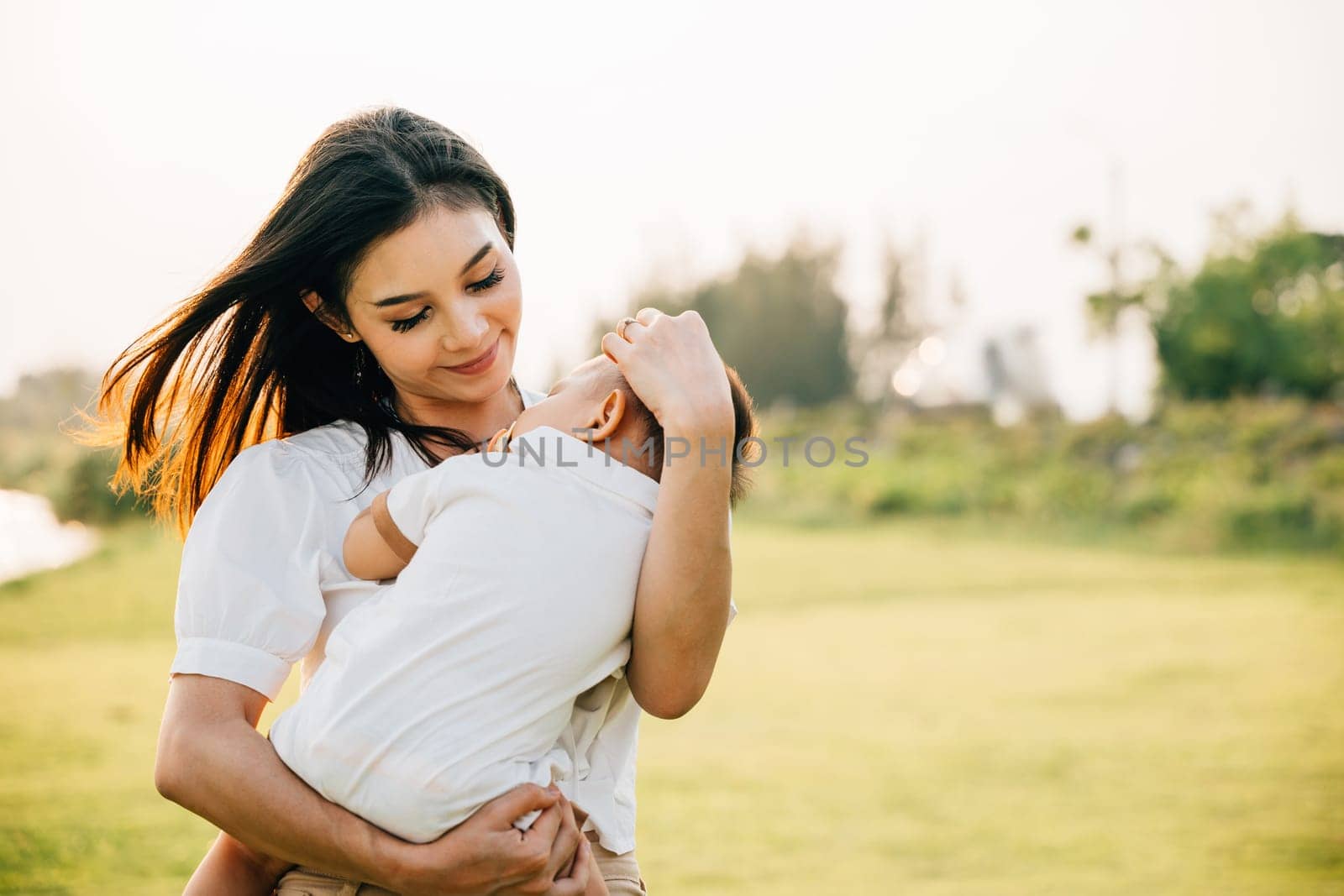 Happy beautiful mother holding baby sleeping son in the park by Sorapop