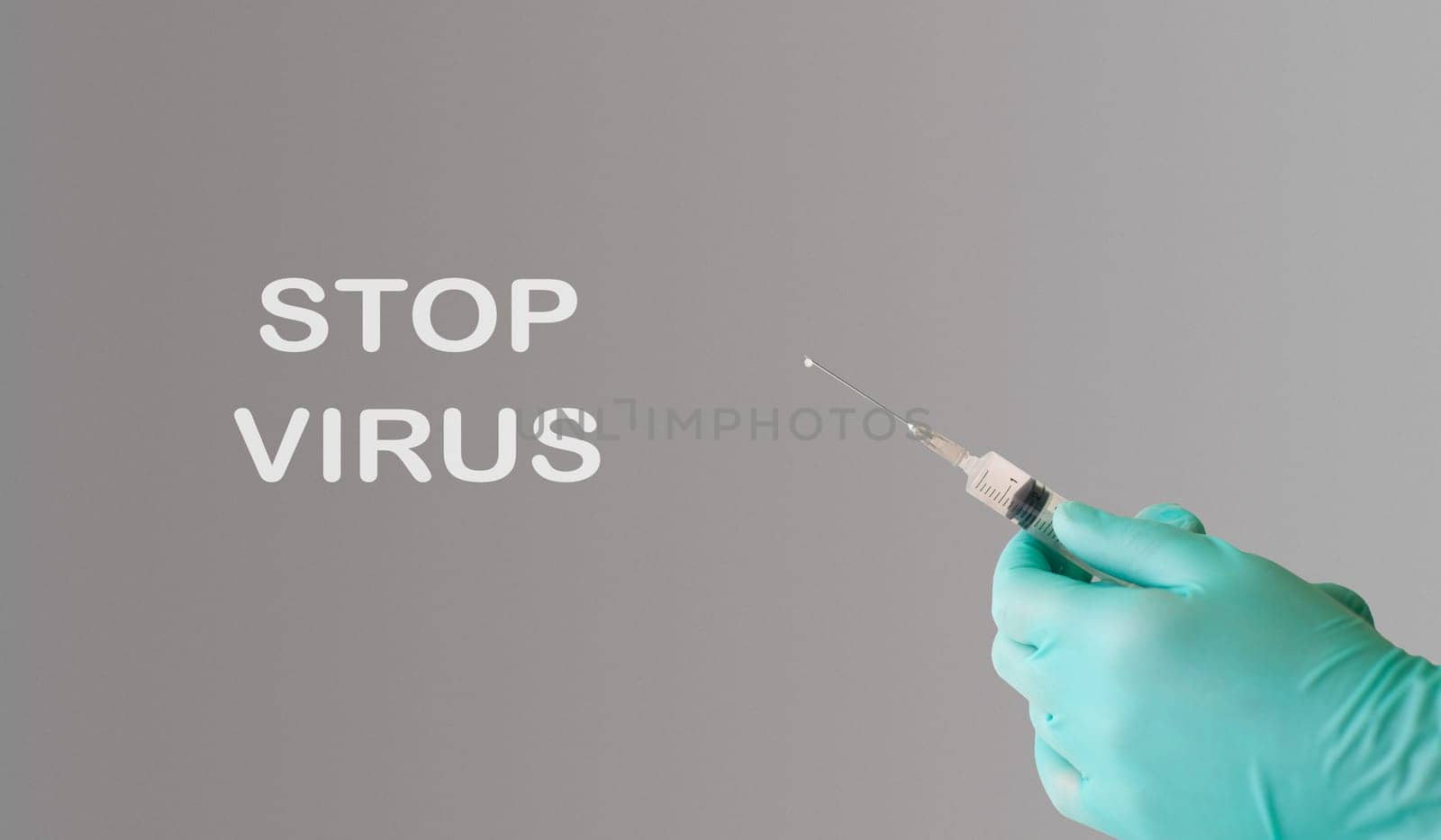 A person holding a syringe with the words Stop Virus written on the wall behind them. Concept of urgency and importance in stopping the spread of viruses