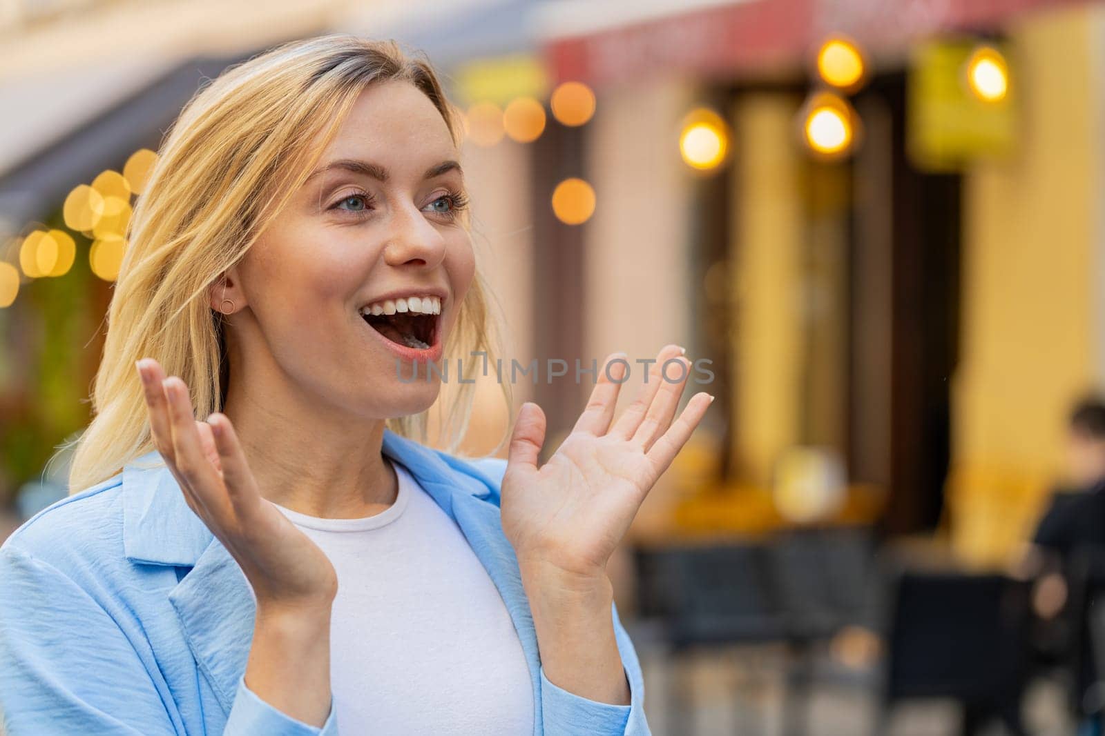 Oh my God, wow. Caucasian young woman looking surprised at side with big open eyes shocked by sudden victory, game winning, lottery goal achievement, good news outdoors. Lady on city sunshine street