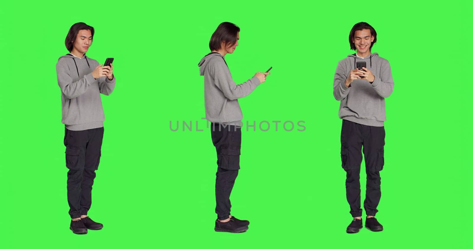 Adult texting messages on phone standing over greenscreen background, using social media app to chat remotely with friends. Asian joyful person messaging on modern smartphone.