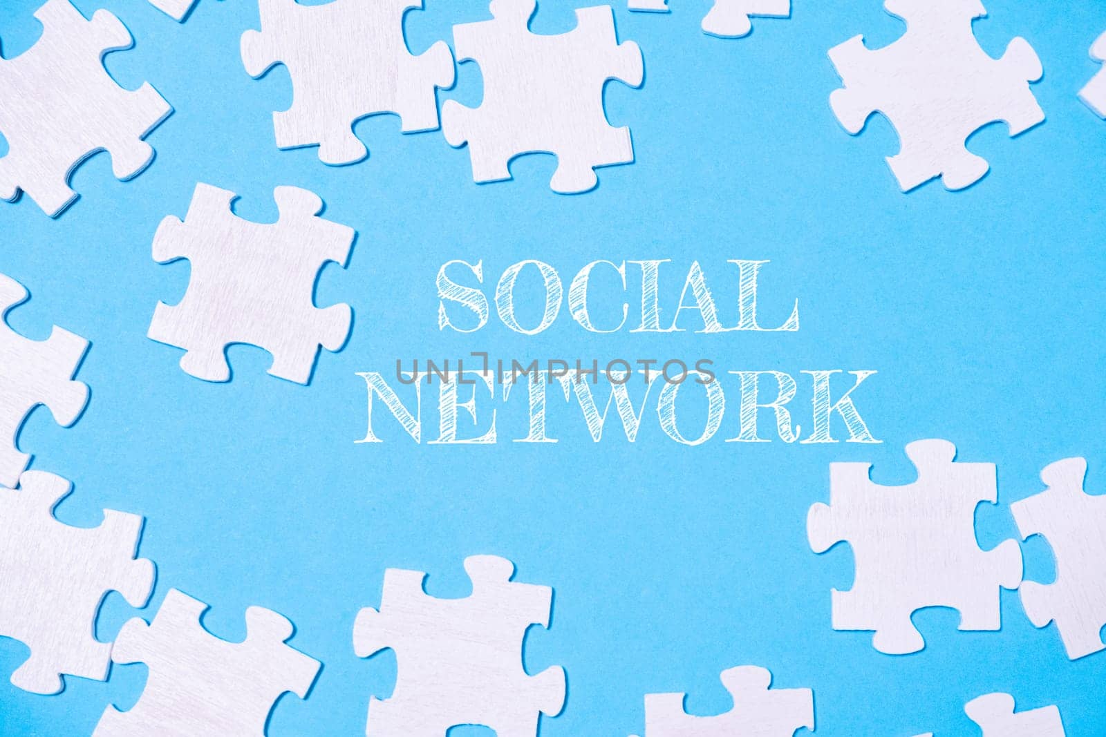 A jigsaw puzzle with the word social network written on it. The puzzle pieces are scattered across the image, creating a sense of disarray and complexity. The blue background adds a calming
