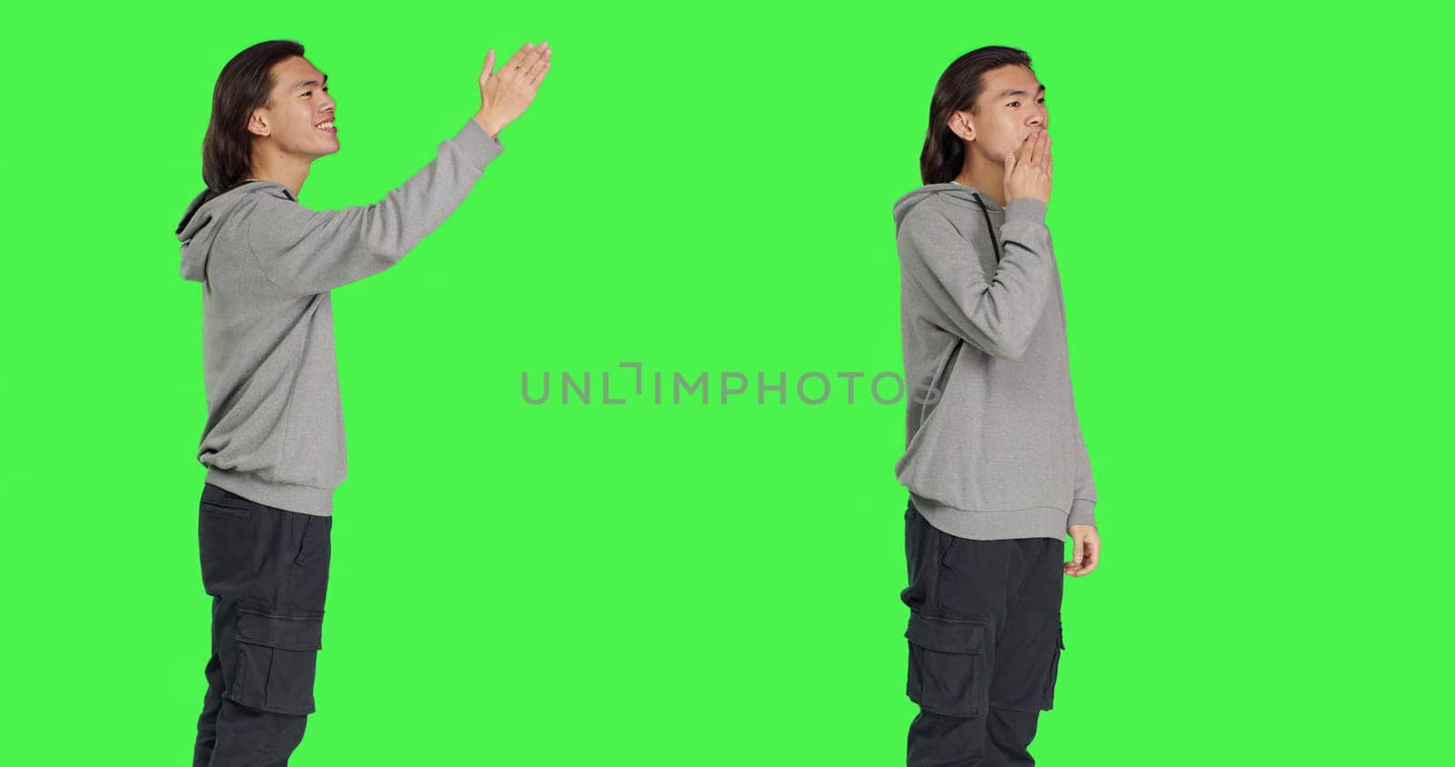 Asian guy sending air kisses on camera, acting romantic and cute standing against greenscreen background studio. Young adult feeling confident and joyful showing true honest emotions.