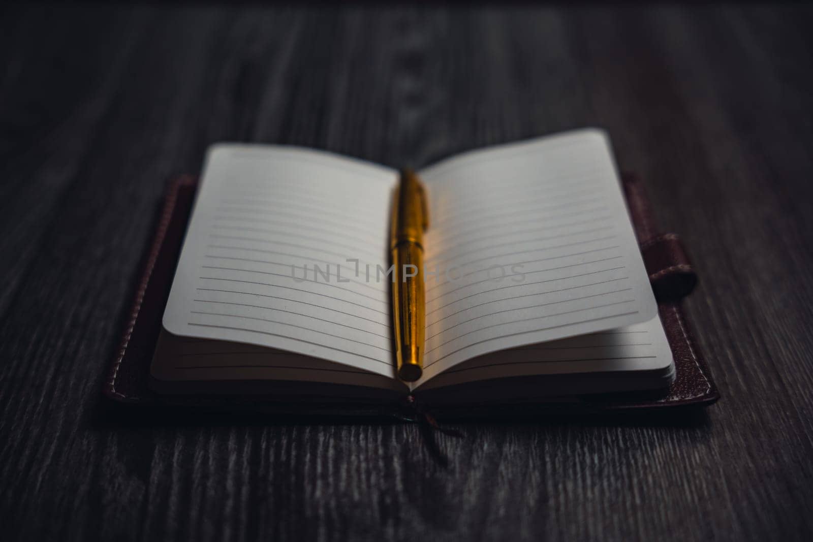 A notebook with a gold pen on the table in the candlelight. High quality photo