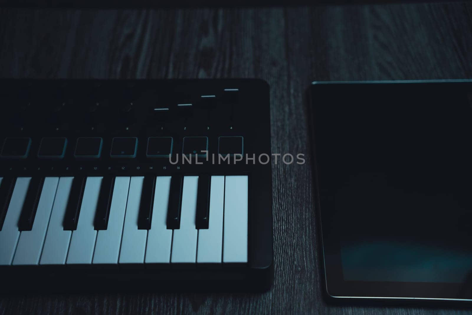 Black midi keyboard on a wooden table. Musical instrument. High quality photo