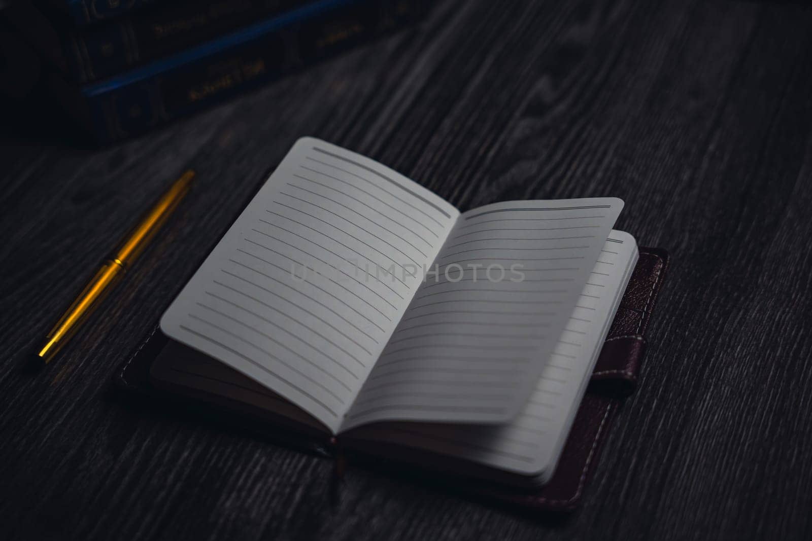 A notebook with a gold pen on the table in the candlelight. High quality photo