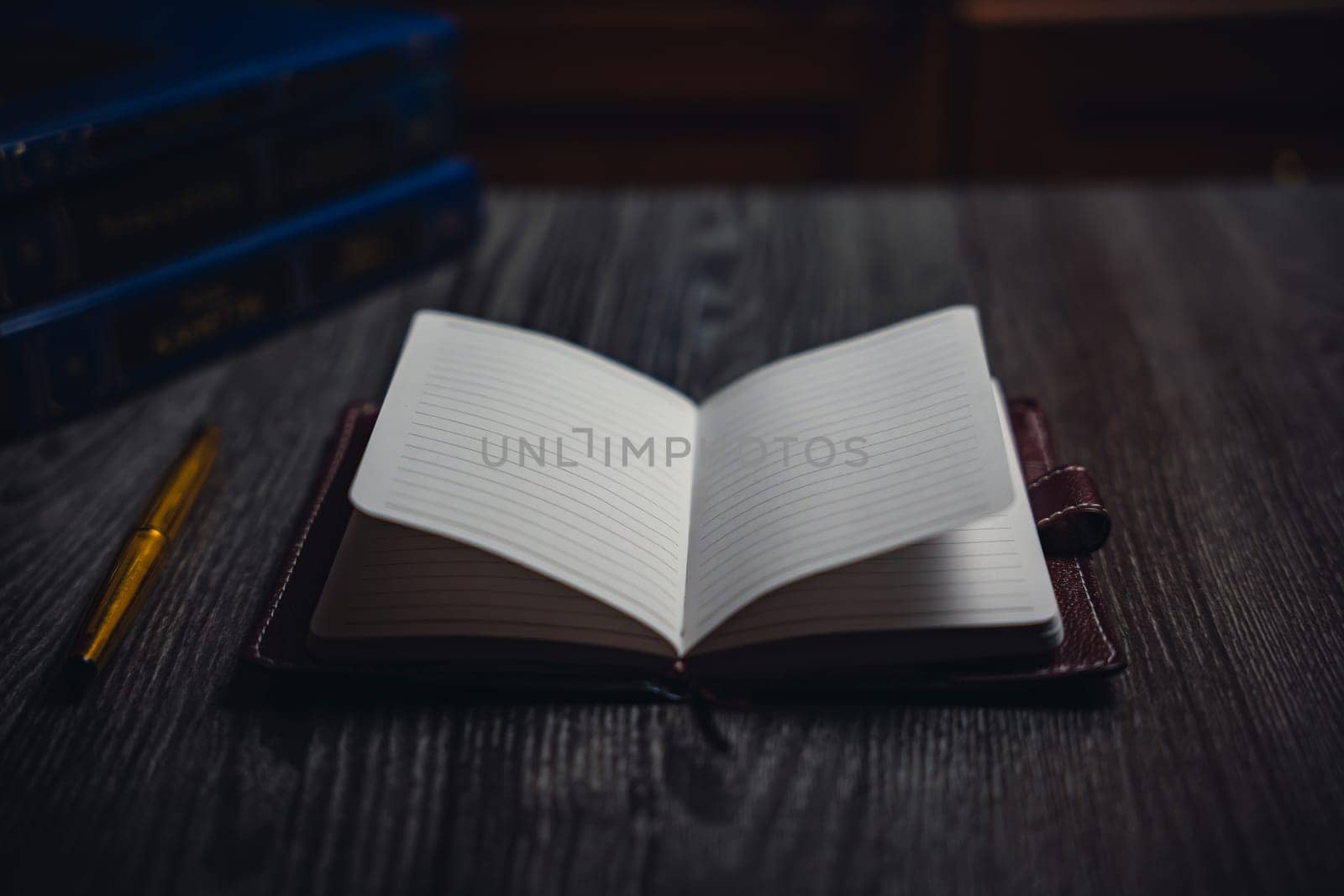 A notebook with a gold pen on the table in the candlelight. High quality photo