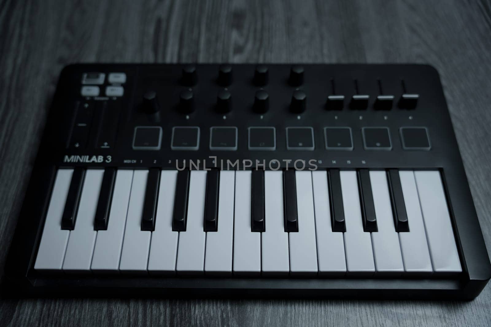 Black midi keyboard on a wooden table. Musical instrument. High quality photo