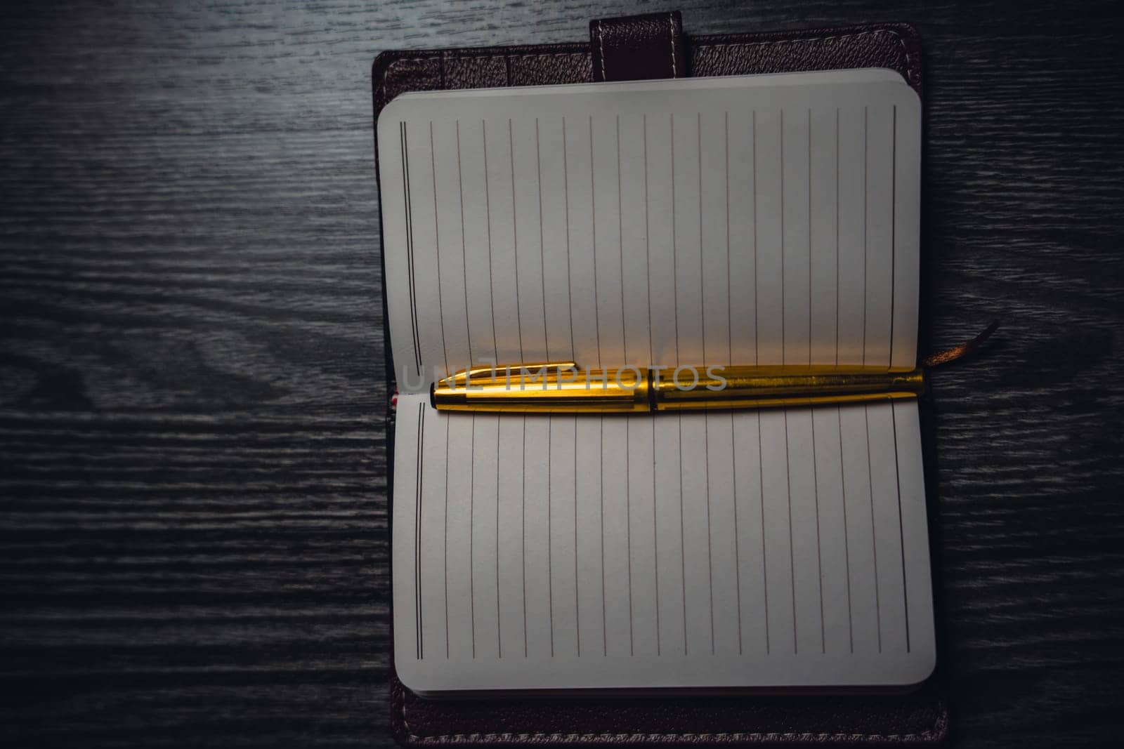 A notebook with a gold pen on the table in the candlelight. High quality photo