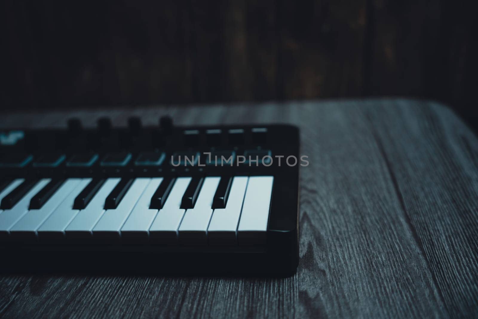 Black midi keyboard on a wooden table. Musical instrument. High quality photo