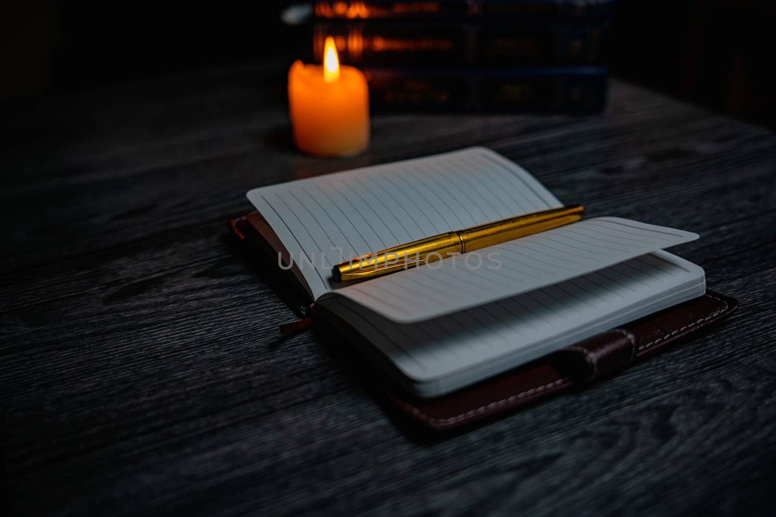 A notebook with a gold pen on the table in the candlelight. High quality photo