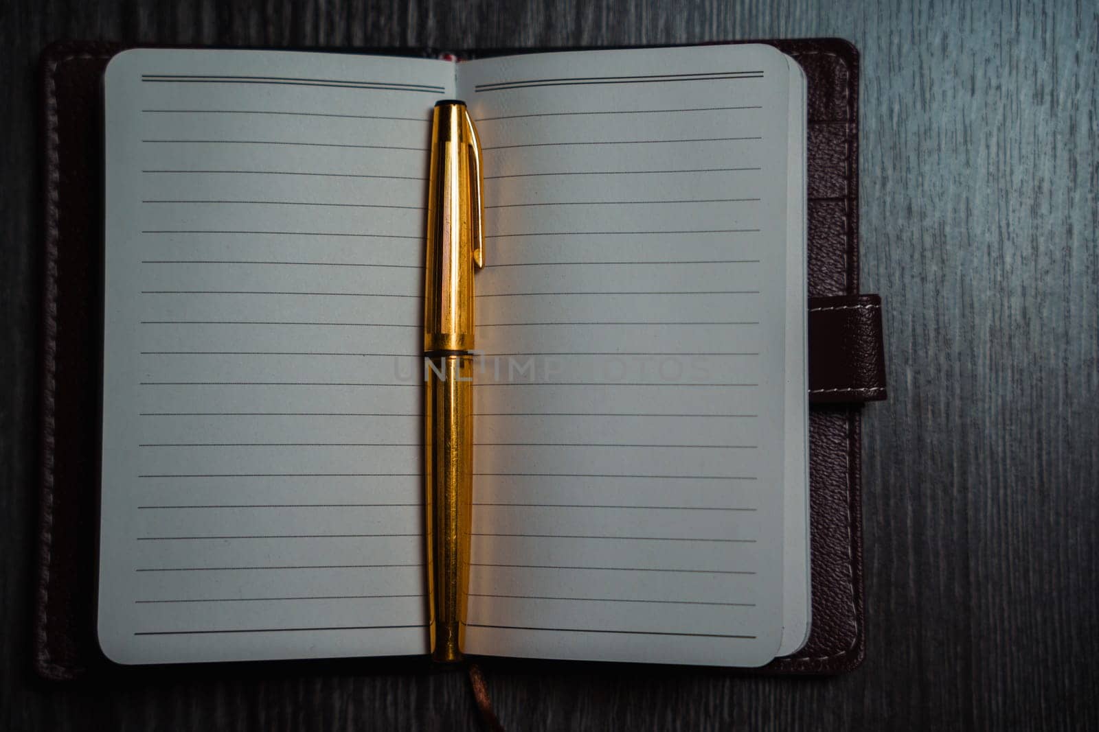 A notebook with a gold pen on the table in the candlelight. High quality photo