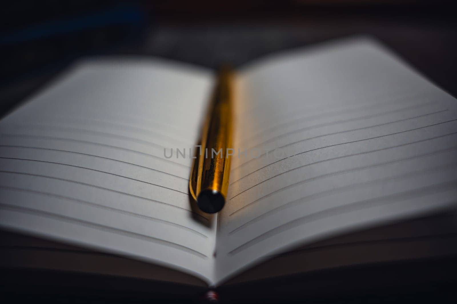 A notebook with a gold pen on the table in the candlelight. High quality photo