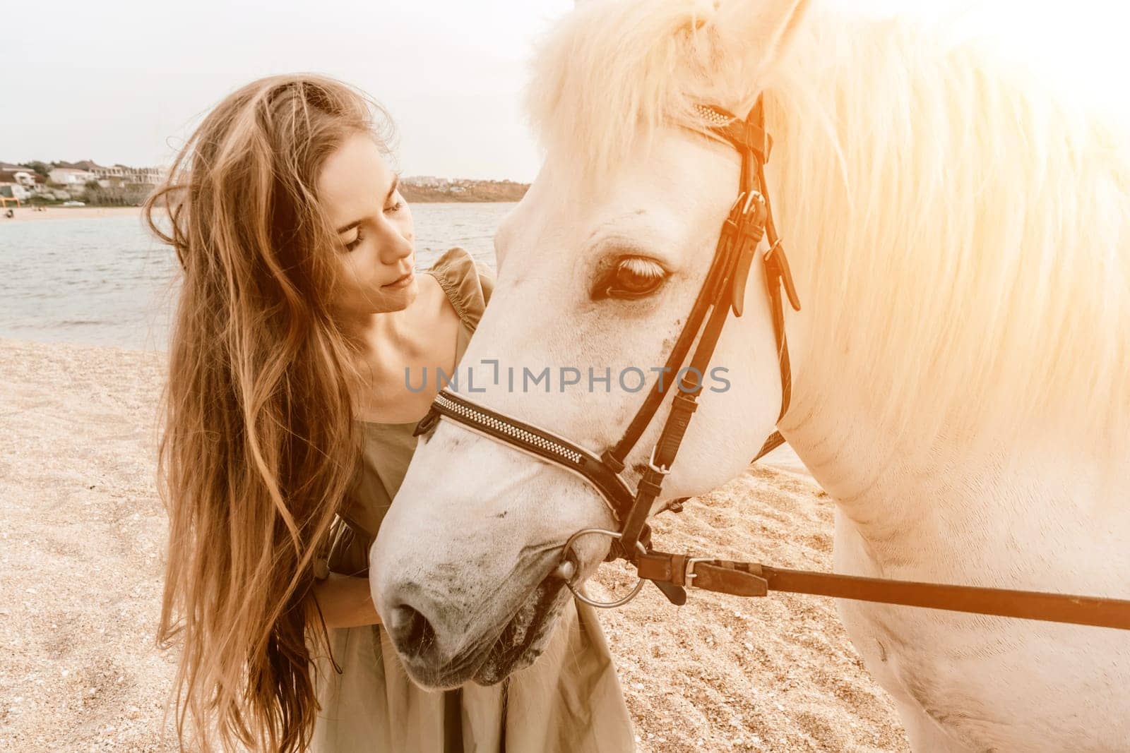 A white horse and a woman in a dress stand on a beach, with the sky and sea creating a picturesque backdrop for the scene