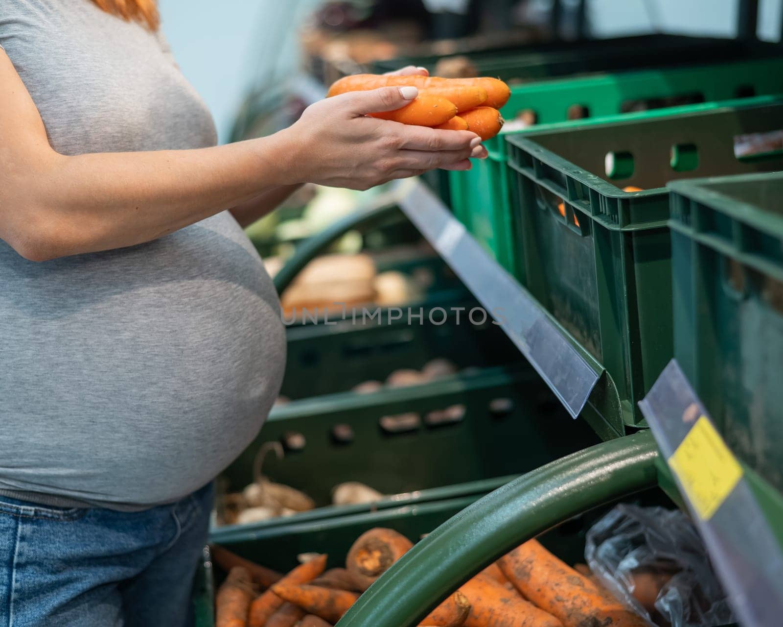Pregnant woman buys carrots in the store