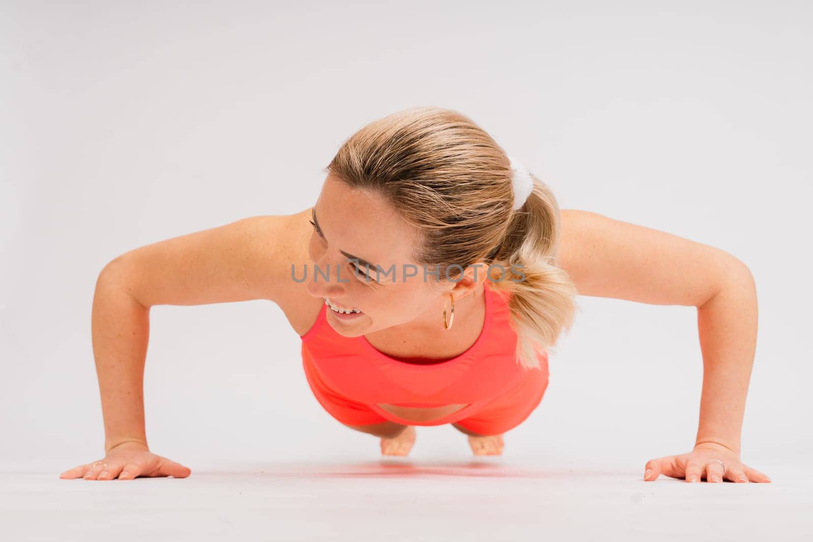 Full length portrait of smiling young woman in a sportswear isolated over studio background.