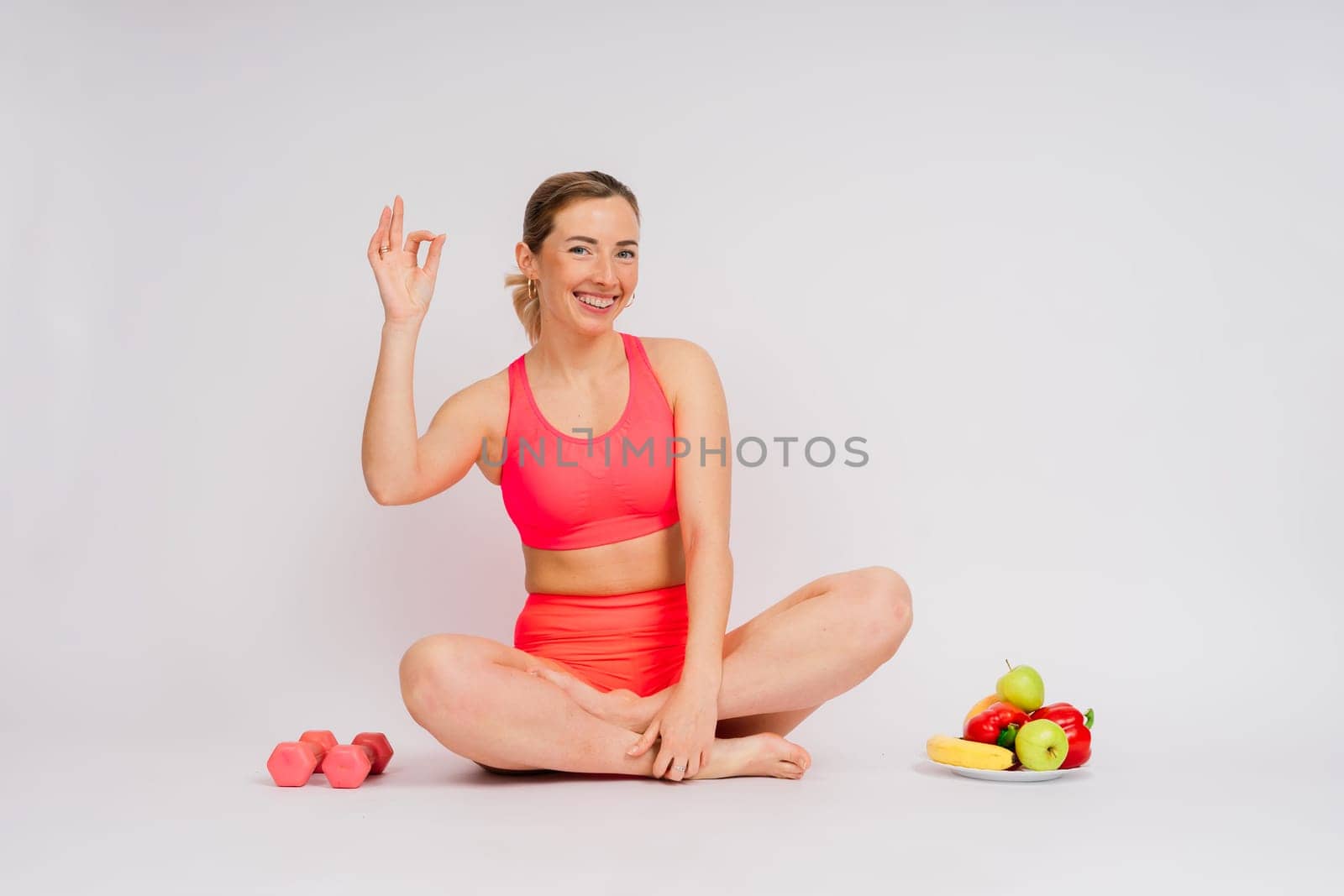 Studio shot of young fitness woman in sports clothing holding green apple, fruits, vegetables. by Zelenin
