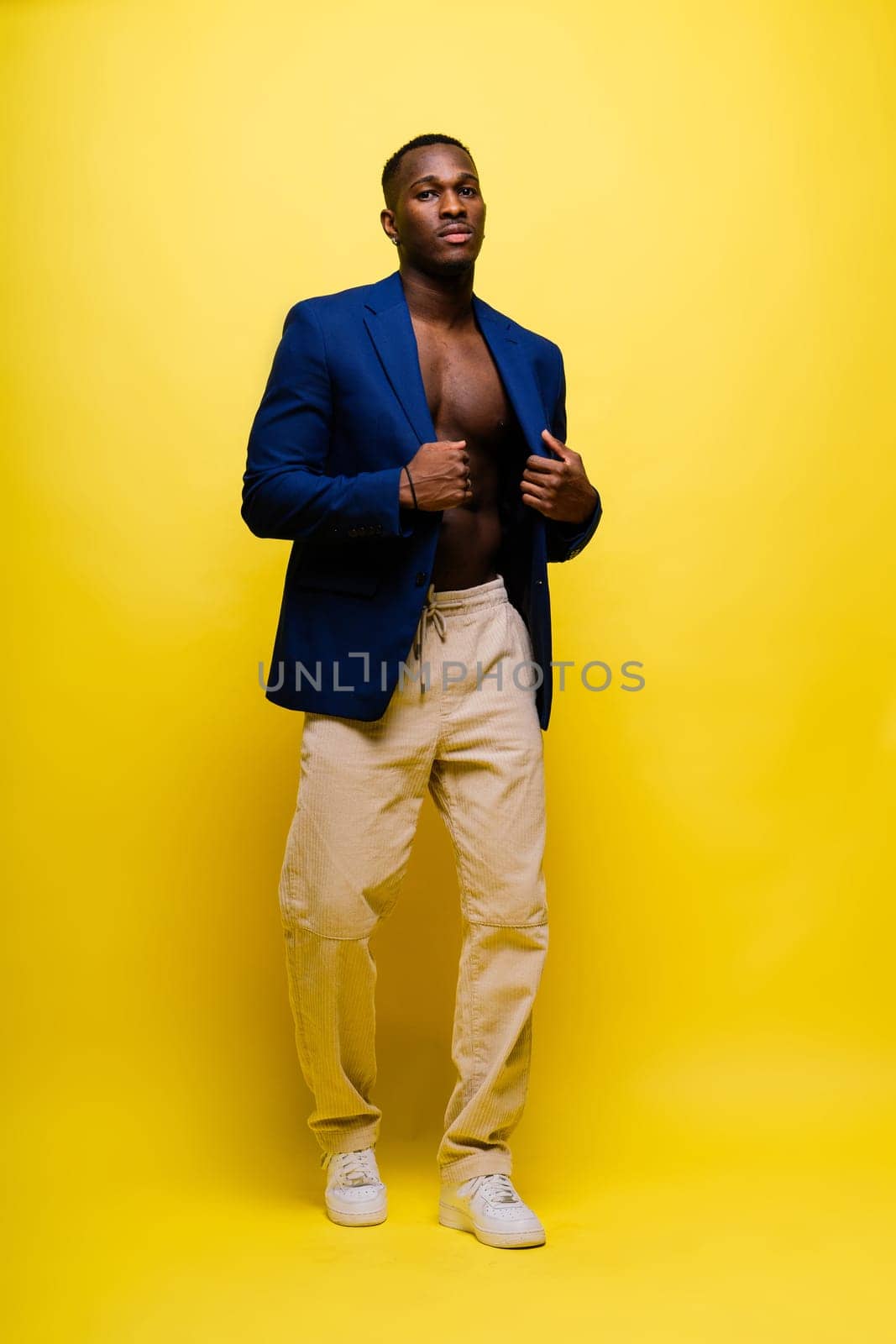 Guy in blue suit on a yellow background. Handsome athletic man in jacket smiling