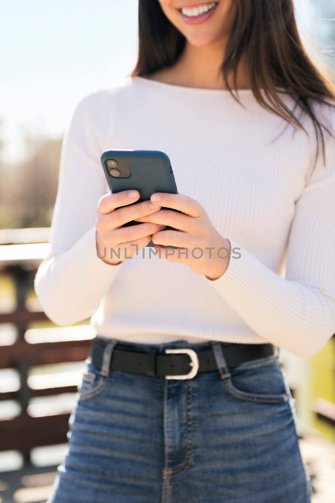 unrecognizable young caucasian woman using mobile phone outdoors, concept of technology of communication and modern lifestyle