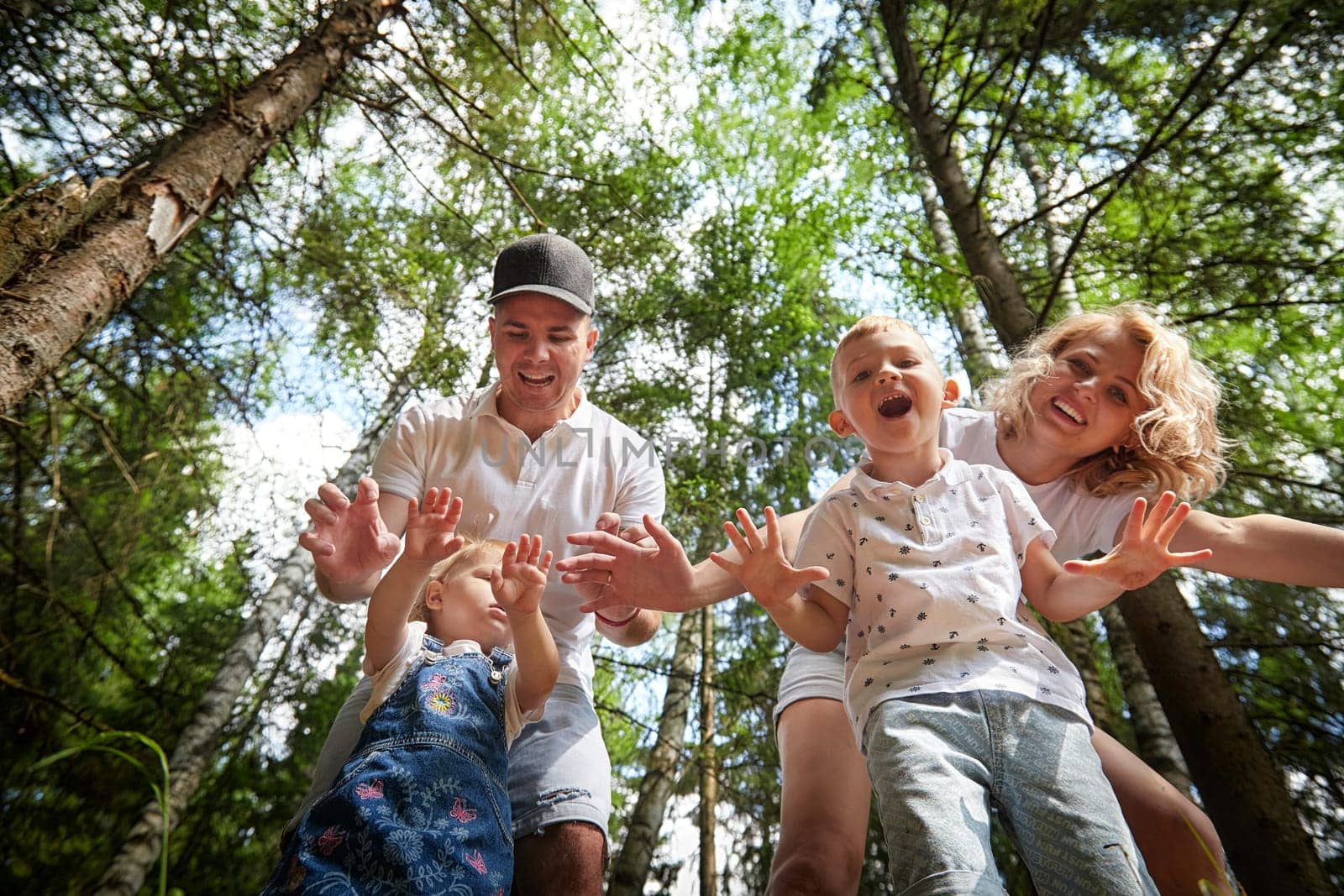 A man, woman, and child having fun and playing in the forest or park in summer or spring sunny day by keleny