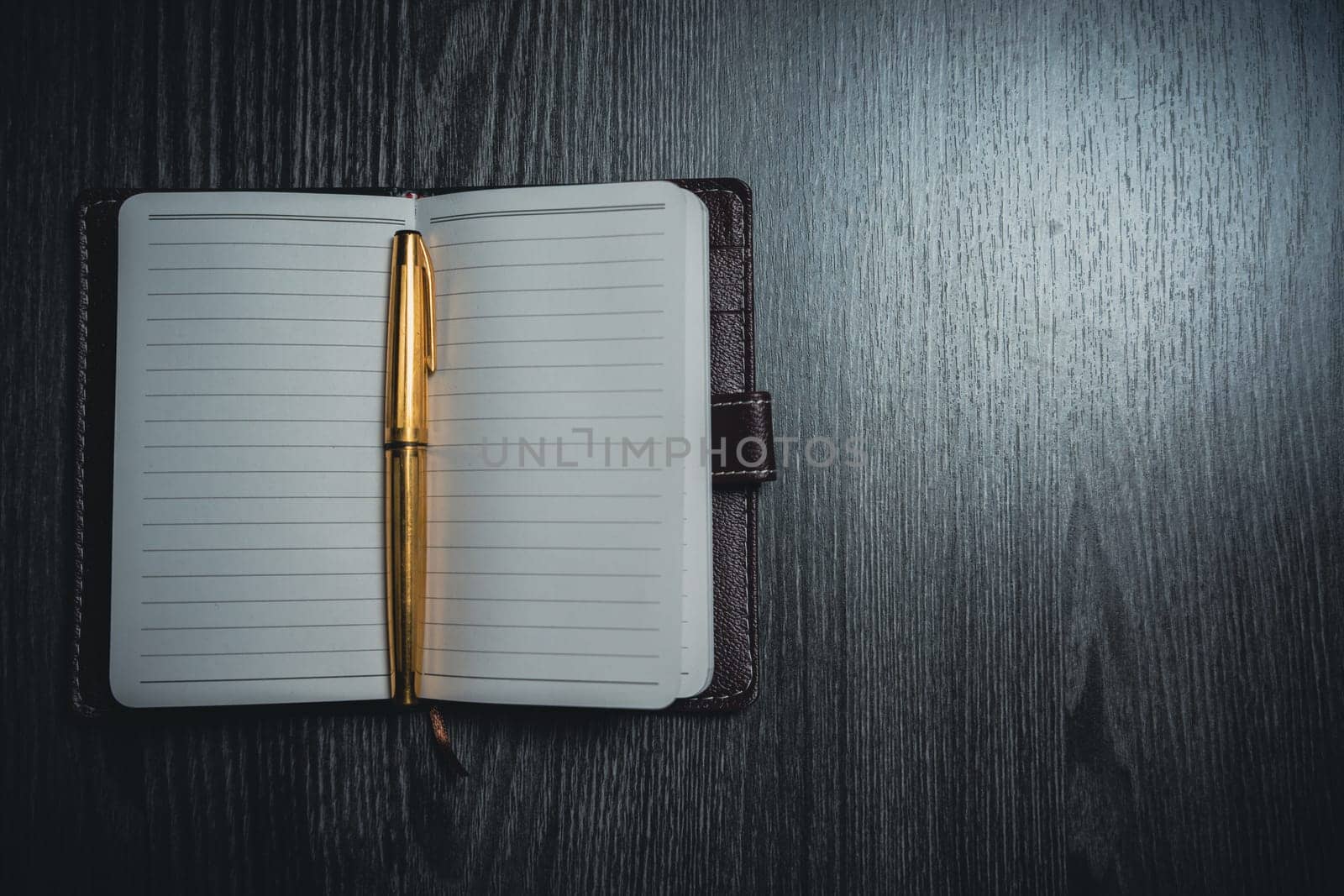 A notebook with a gold pen on the table in the candlelight. High quality photo