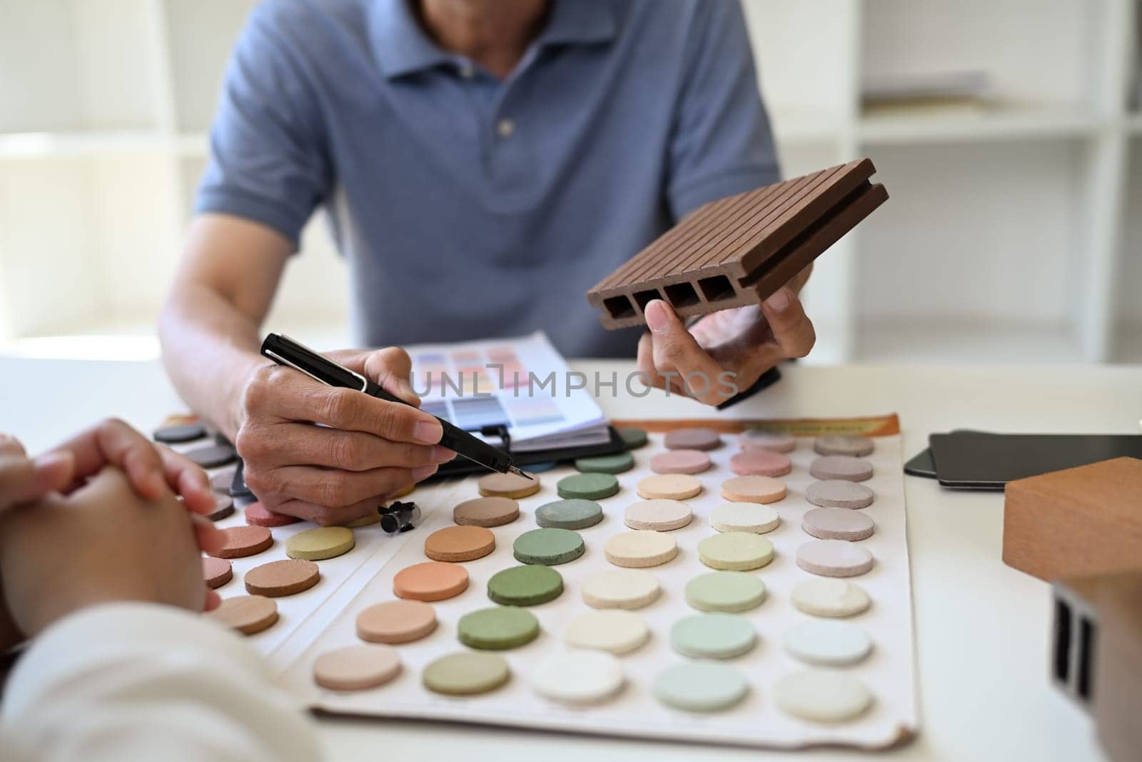 Closeup professional interior designer helping client choosing colors in swatches palette for apartment renovation.