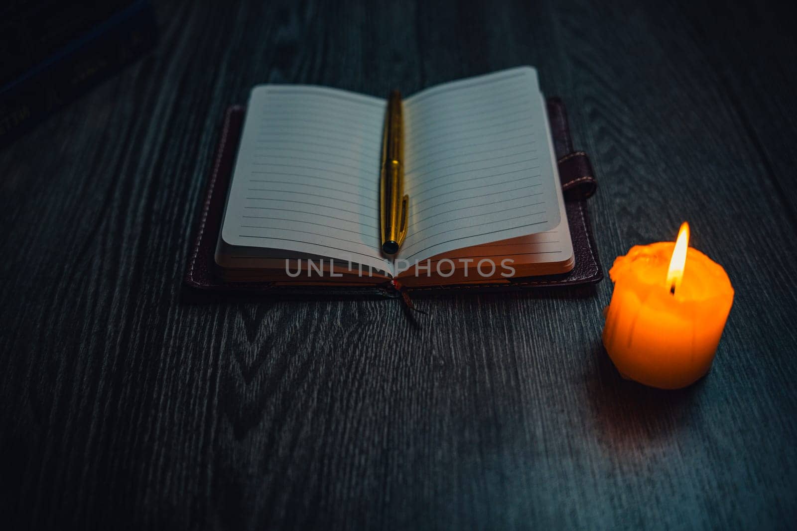 A notebook with a gold pen on the table in the candlelight. High quality photo