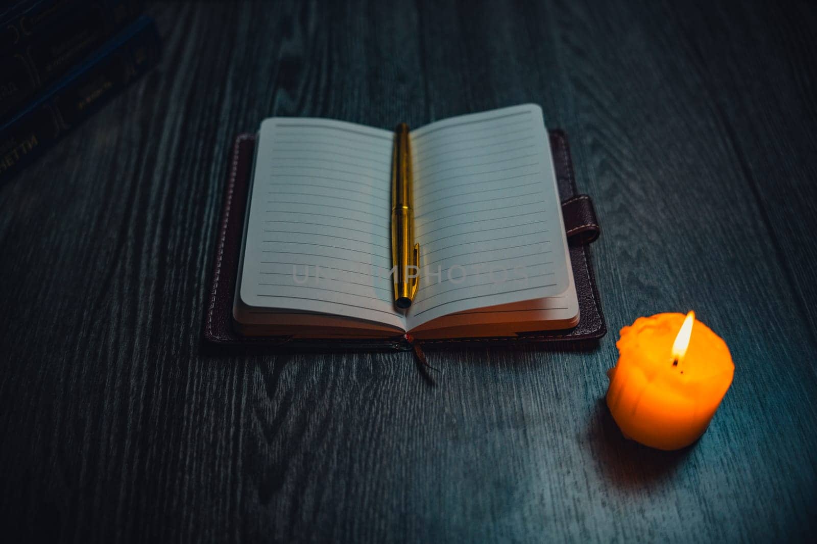 A notebook with a gold pen on the table in the candlelight. High quality photo