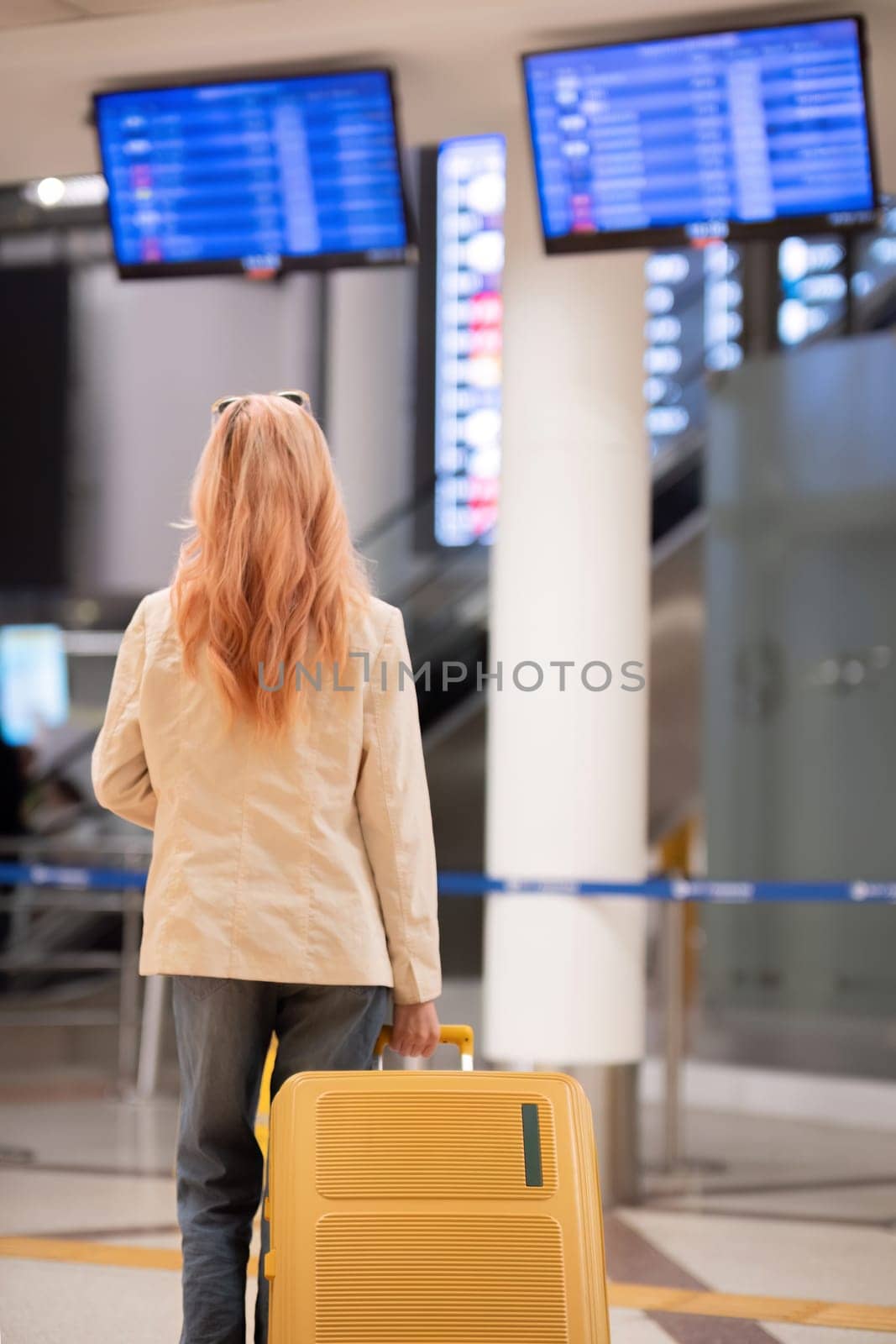 Young woman with luggage checking flight information at airport terminal. Concept of travel, preparation, and anticipation by wichayada