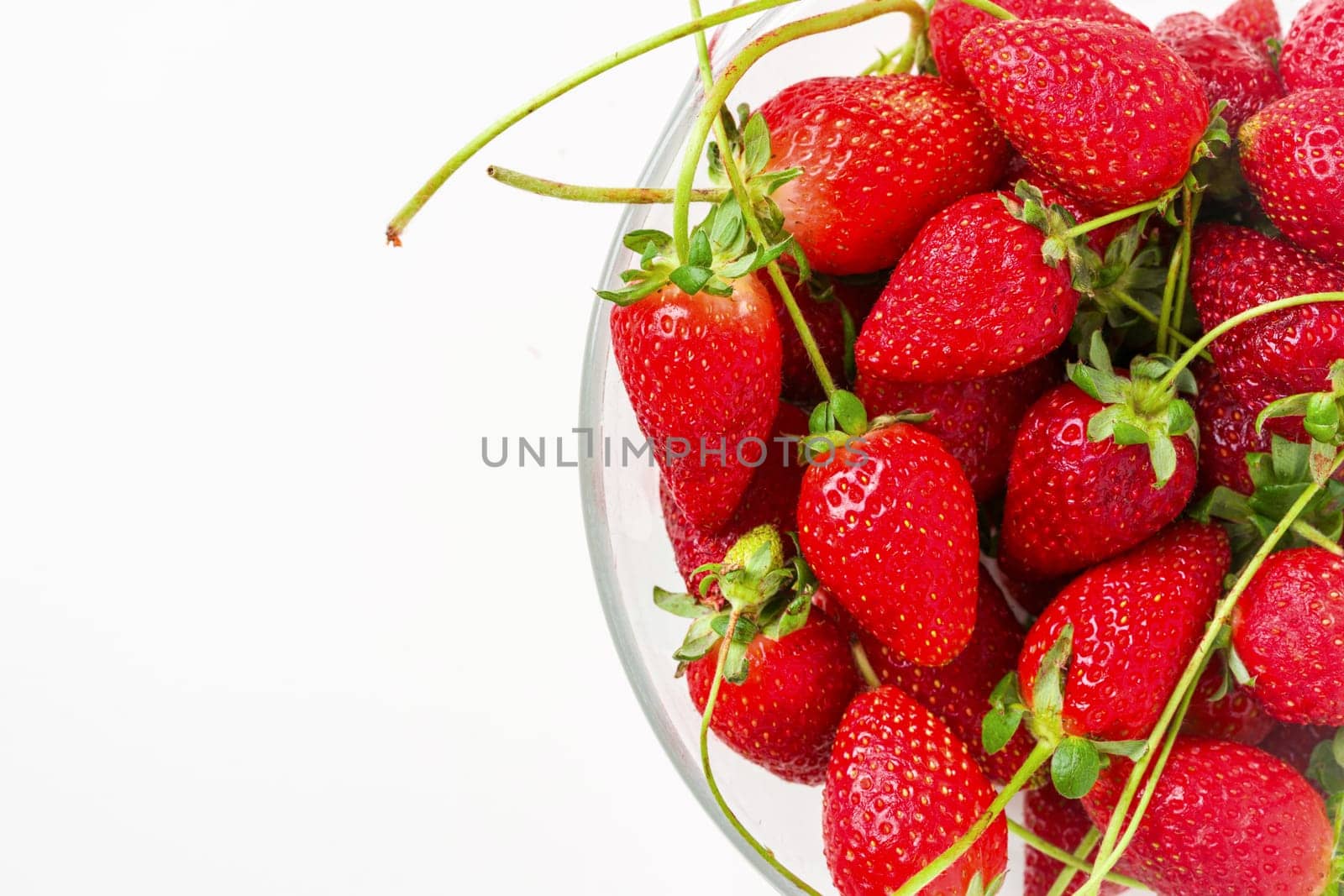 Top view of strawberries in glass bowl on white background