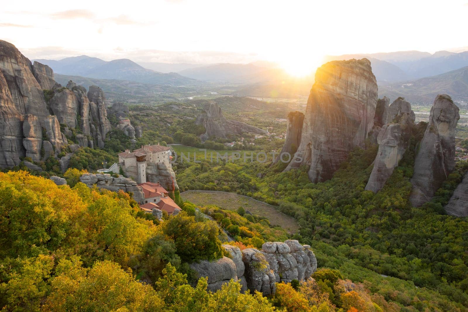 Greece. Monastery on the rock. Sunset rays over the green Meteora valley