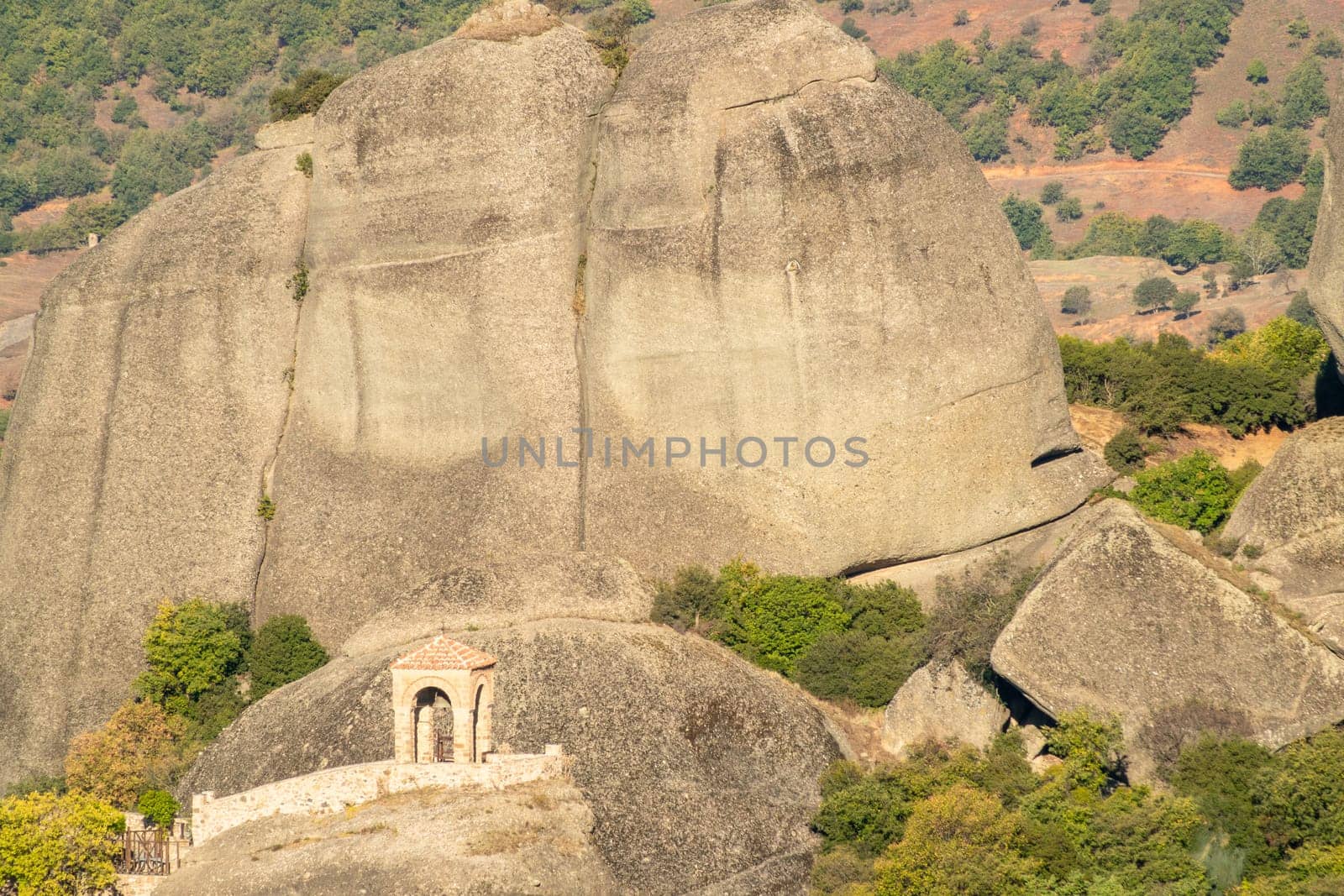 Greece. Sunny summer day in Kalambaka. Small stone gazebo against the backdrop of a large rock in Meteora