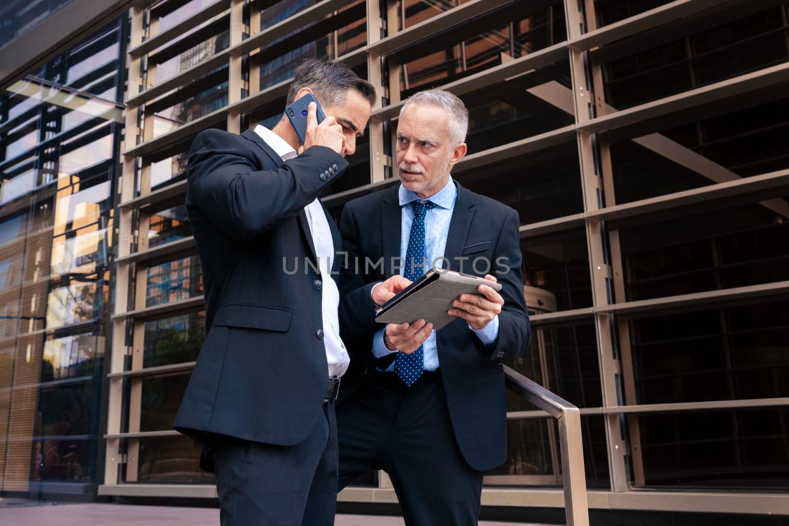 Two trusted business colleagues dressed in formal attire with a digital tablet in hand observing the results of the work done