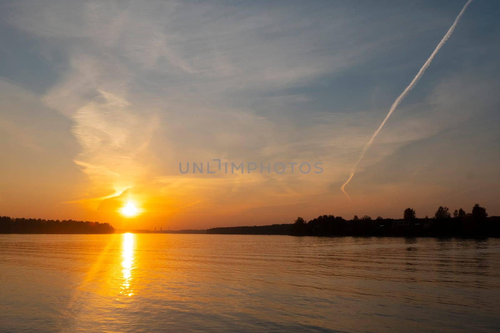 Sunset by river with tree silhouette. High quality photo