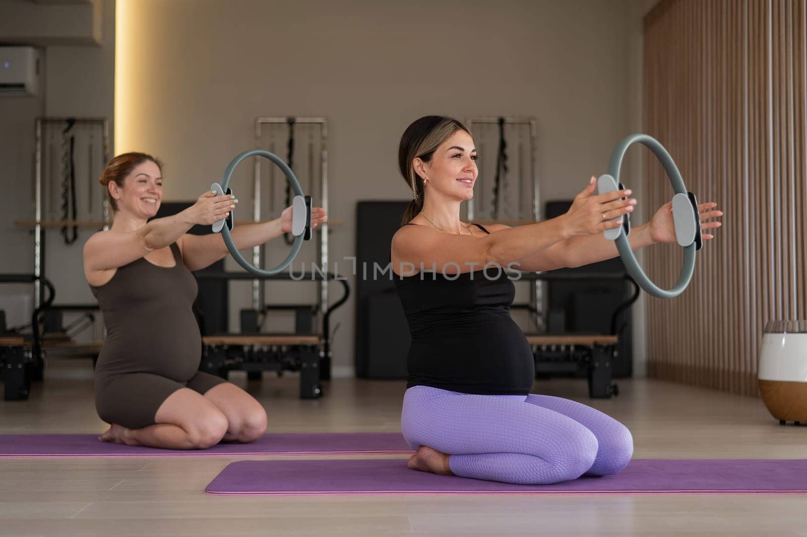 Two pregnant women doing yoga. Exercises with a gymnastic circle for Pilates