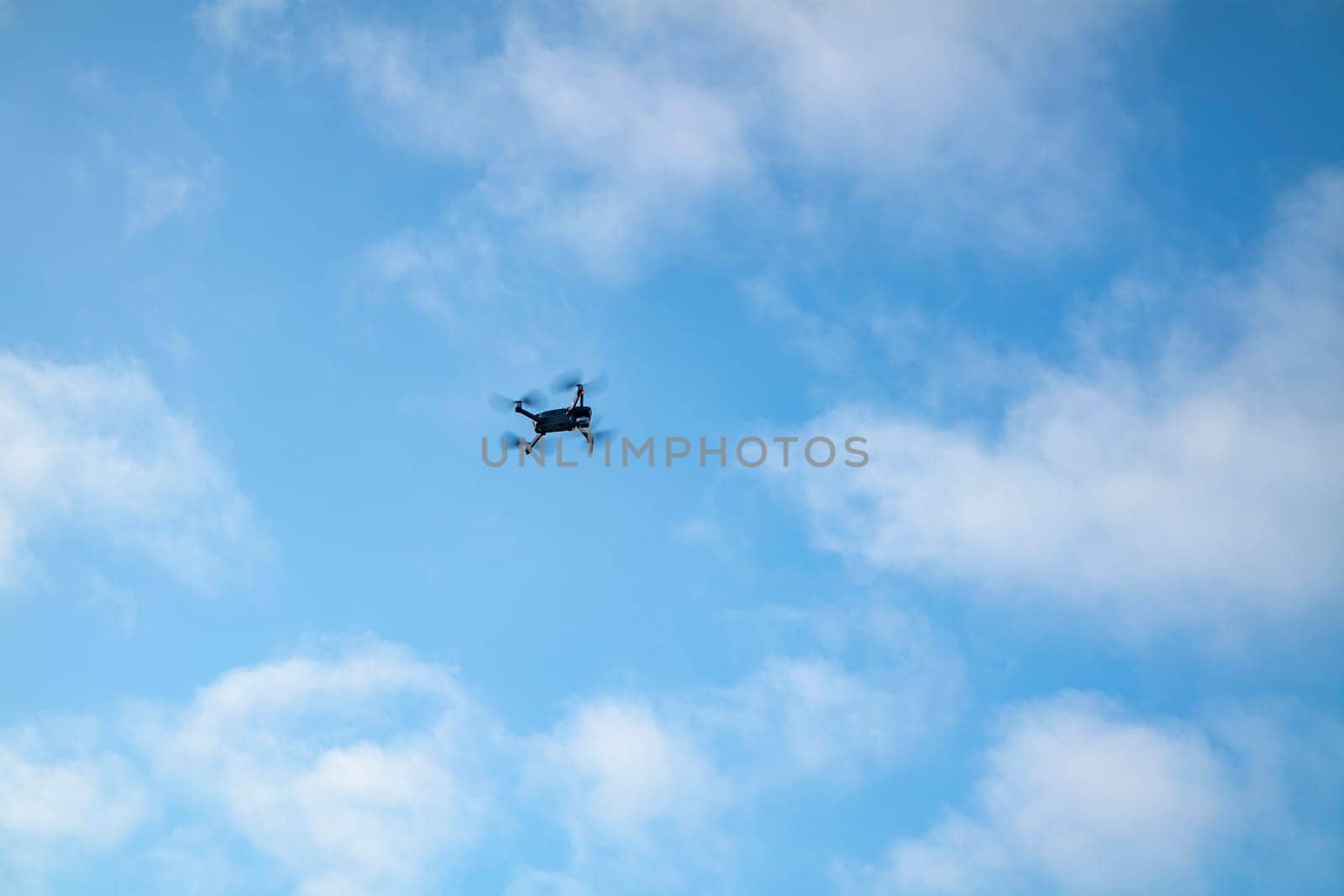 Small drone flying in the blue sky.