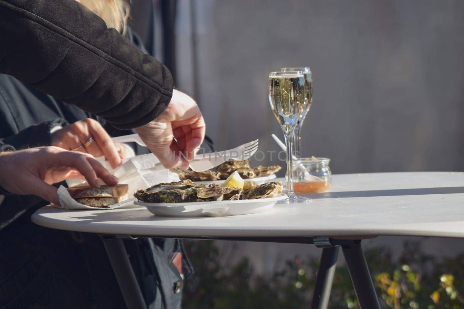 Woman eating fresh oysters at Christmas market in Paris. Selective focus on right hand.