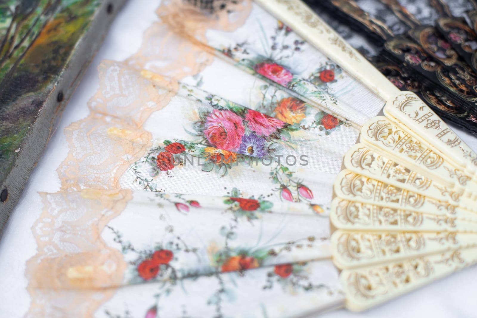 Open white fan with flowers at the flea market