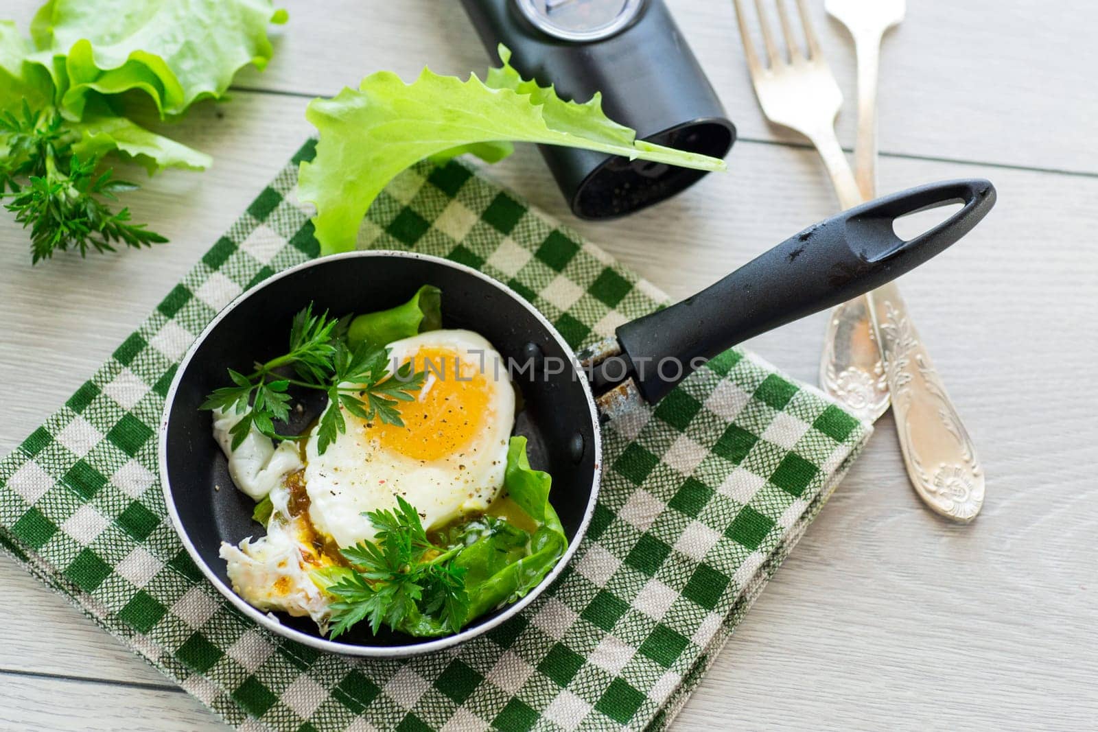 fried egg in a frying pan with herbs .