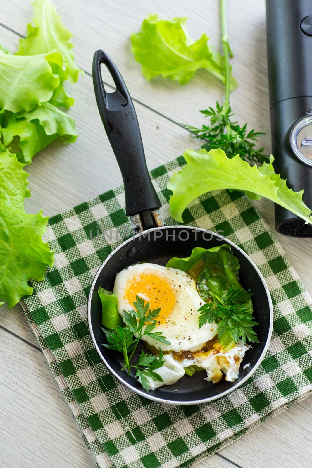 fried egg in a frying pan with herbs .