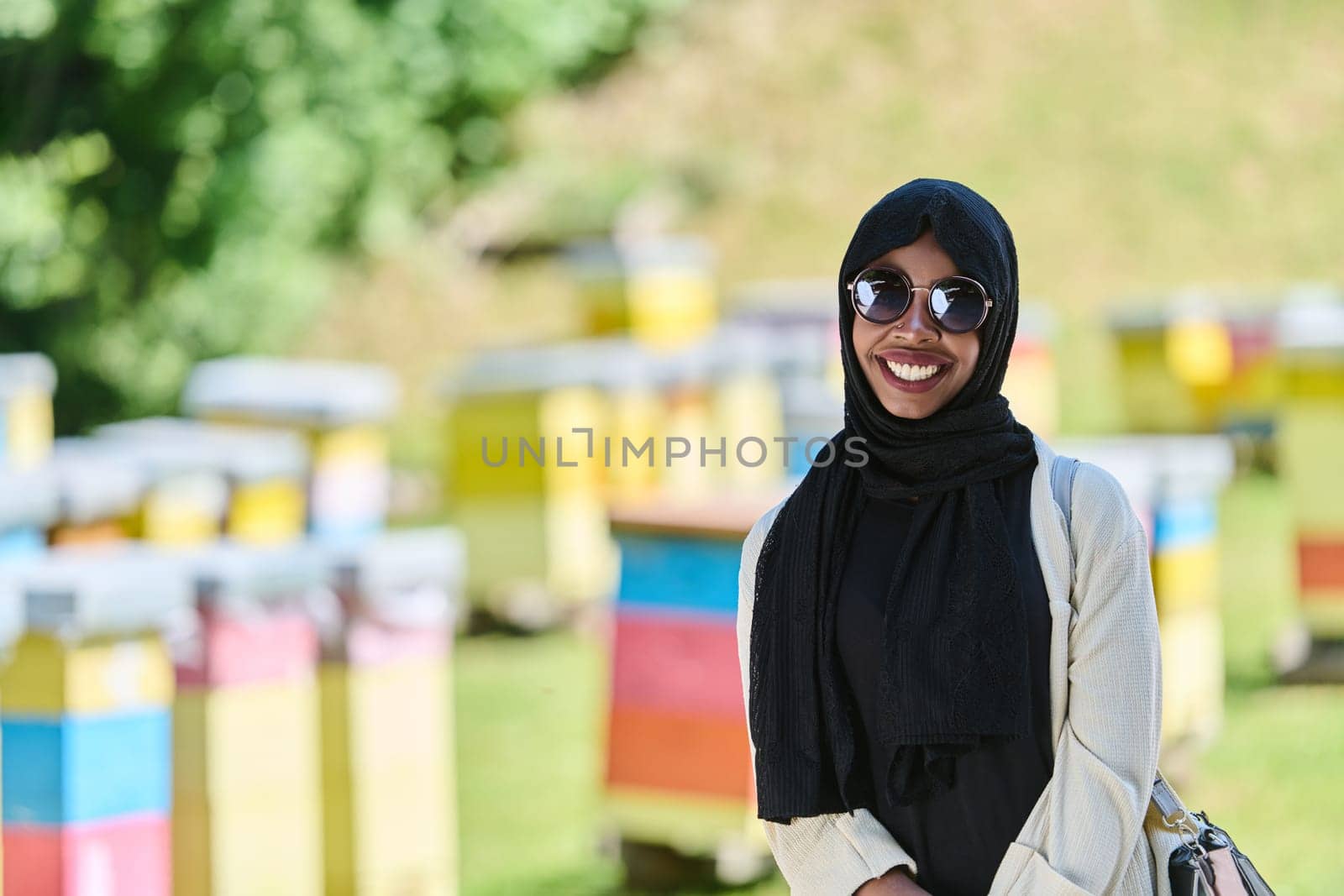 African American Muslim woman in hijab explores natural bee farms for honey production, blending tradition with sustainability in the serene countryside.