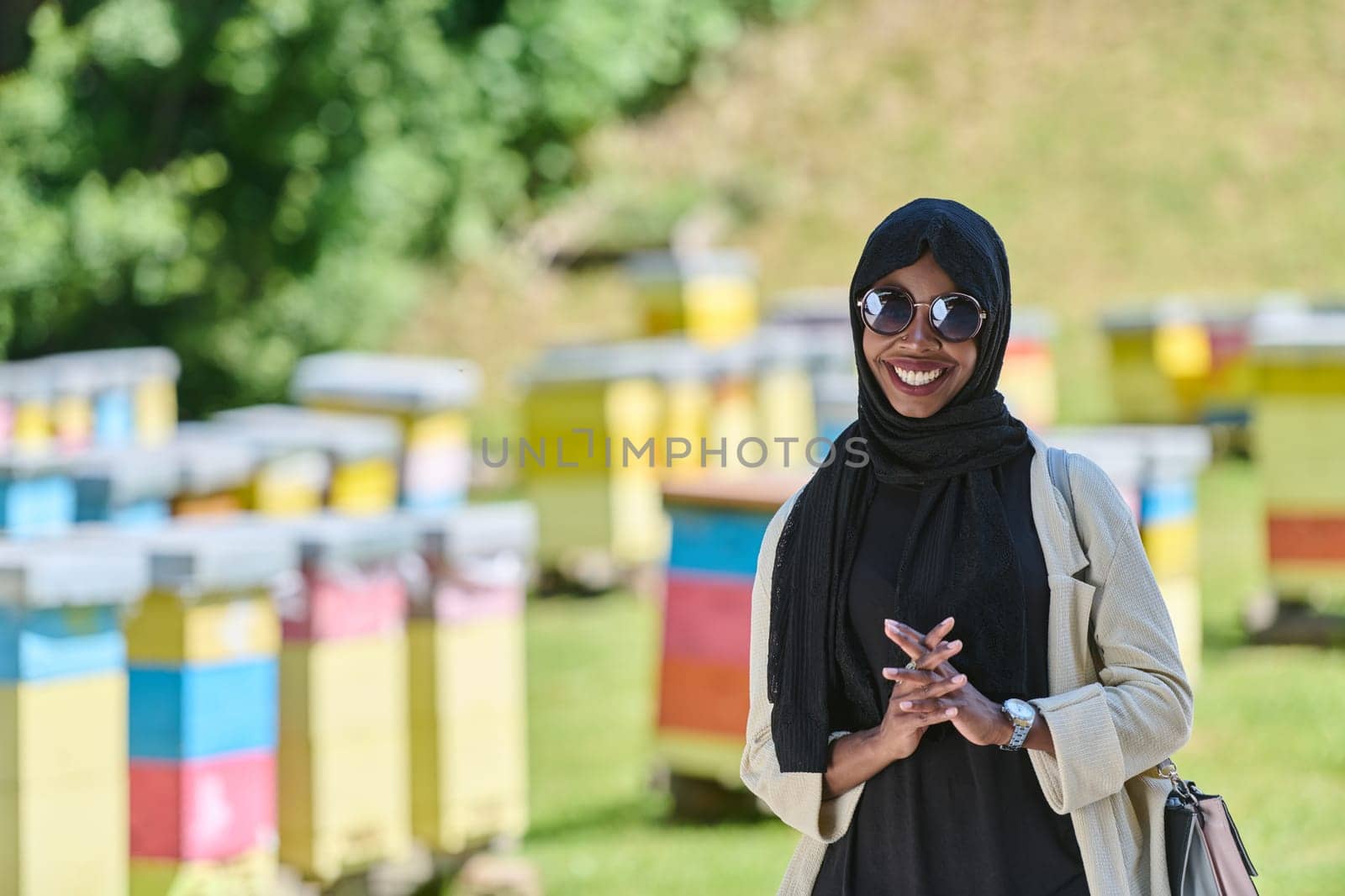 African American Muslim woman in hijab explores natural bee farms for honey production, blending tradition with sustainability in the serene countryside.