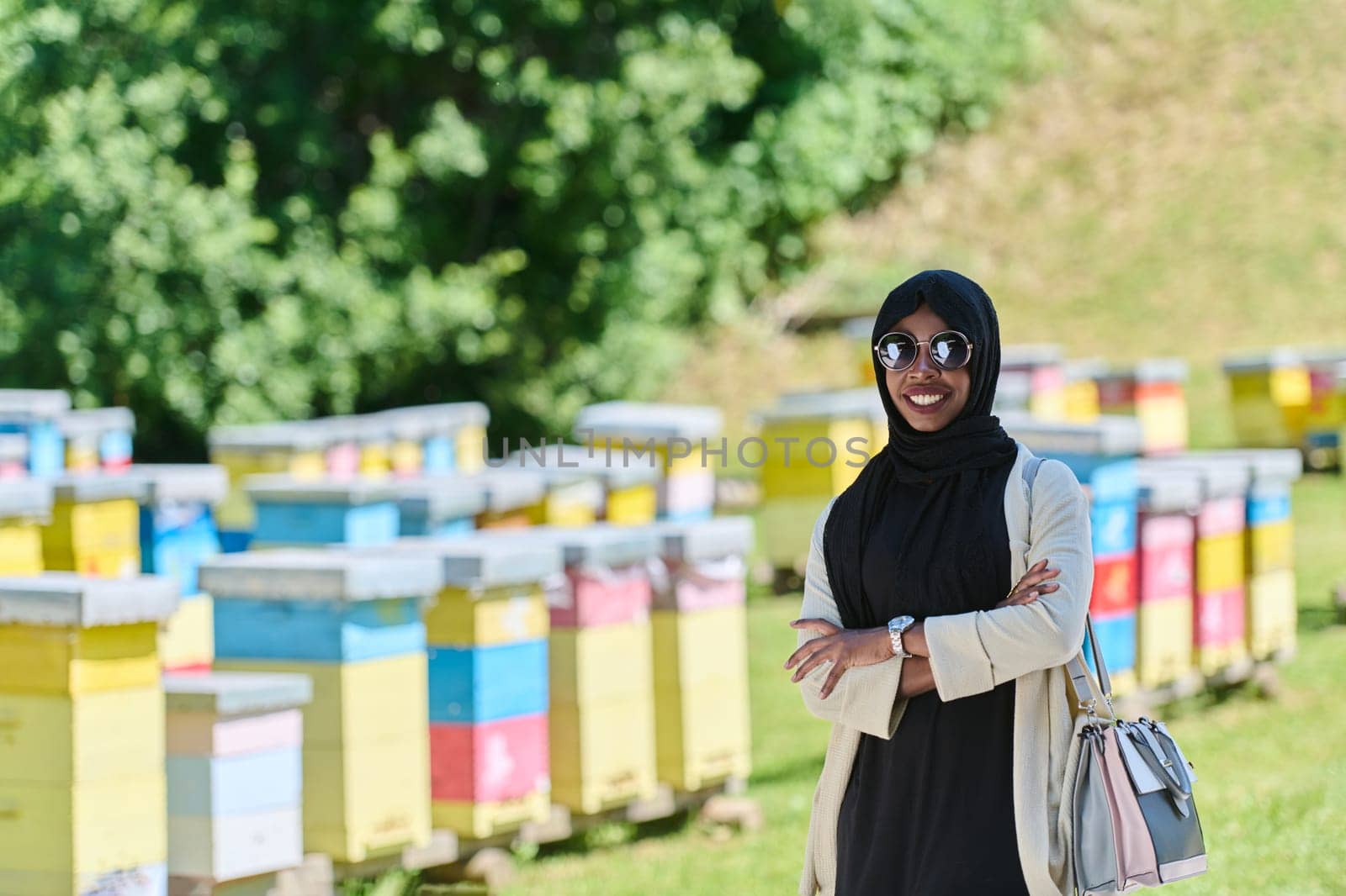 African American Muslim woman in hijab explores natural bee farms for honey production, blending tradition with sustainability in the serene countryside.