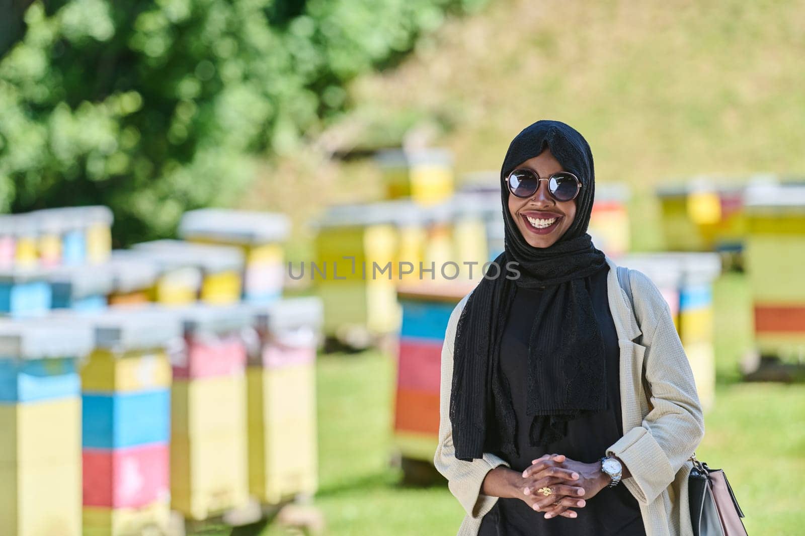 African American Muslim woman in hijab explores natural bee farms for honey production, blending tradition with sustainability in the serene countryside.