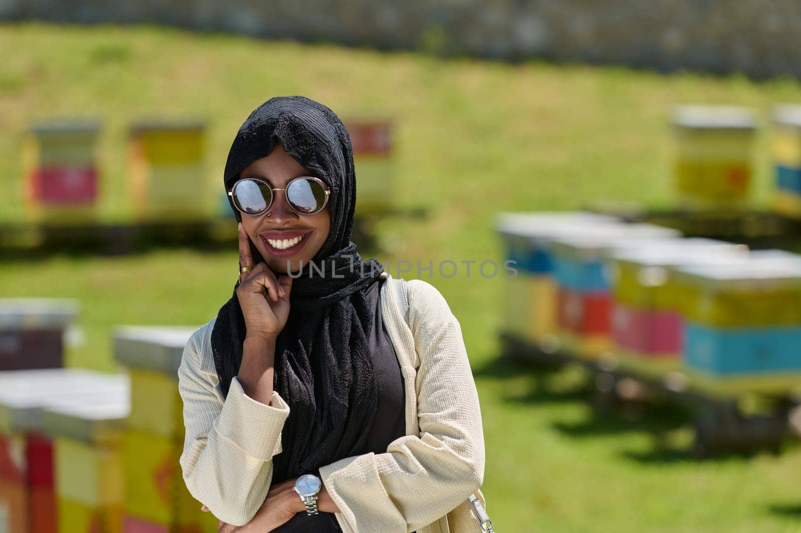 African American Muslim woman in hijab explores natural bee farms for honey production, blending tradition with sustainability in the serene countryside.